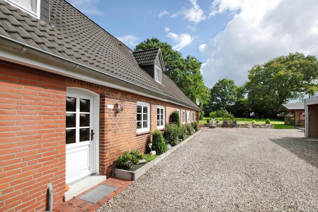 a brick house with a white door and a driveway at Ketelsens Ferienwohnung in Bohmstedt