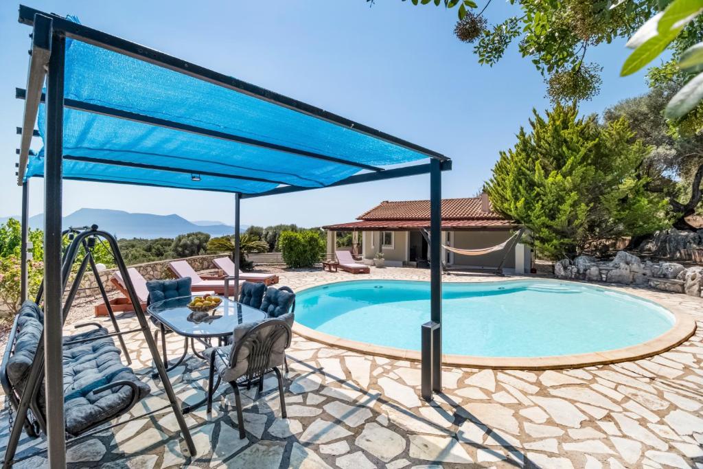 a blue canopy over a pool with a table and chairs at Villa Jimmy's Katomeri 3 in Meganisi