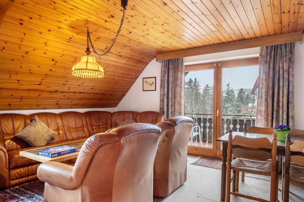 a living room with leather furniture and a wooden ceiling at Haus Irmgard in Lenzkirch