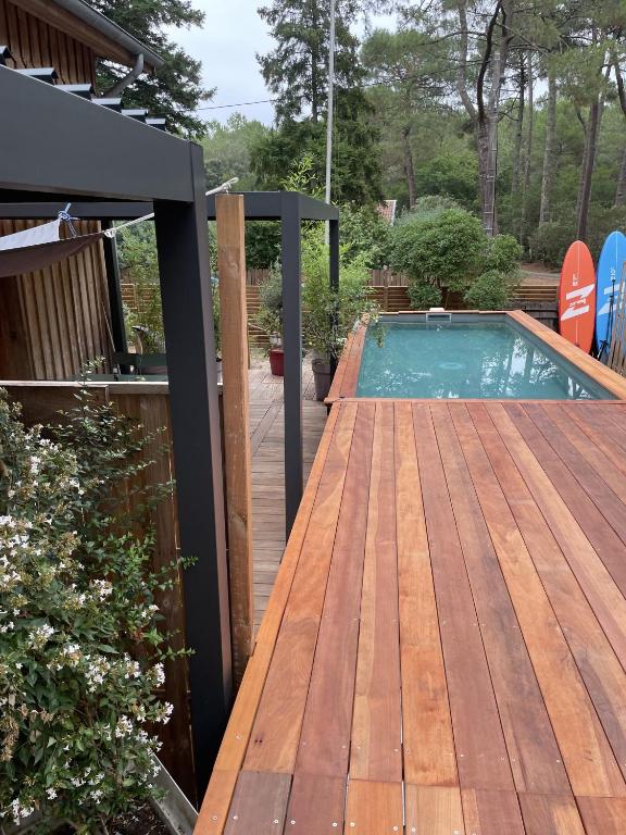 a wooden deck with a swimming pool on a house at La Cabane des P’tits chiffon in Lacanau