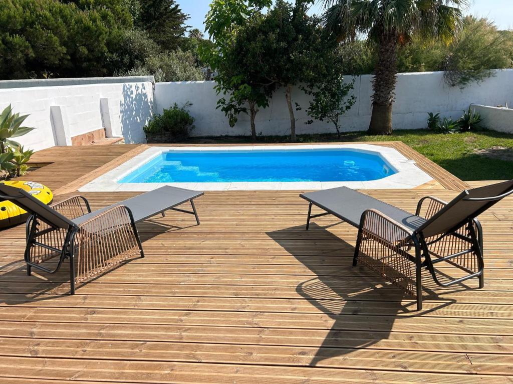 a swimming pool with two chairs and a table and a swimming pool at Casa Luna in Los Caños de Meca