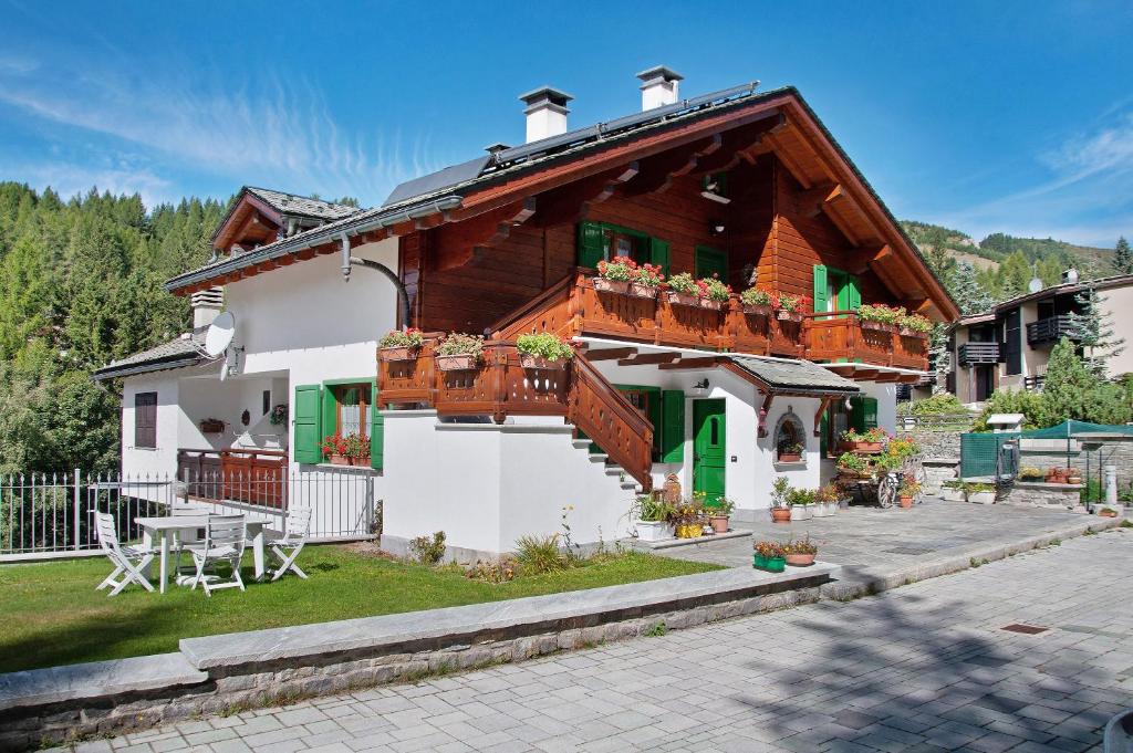 a house with a balcony and a table at Ginepro Casa Vacanze in Madesimo