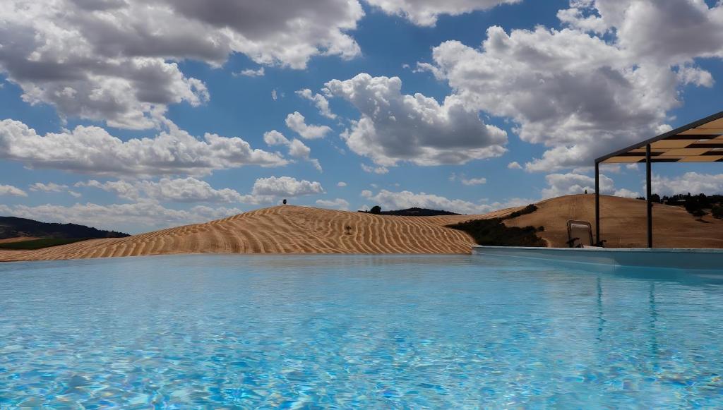 a large pool of water in front of a sand hill at Podere Spagliarda in San Quirico dʼOrcia