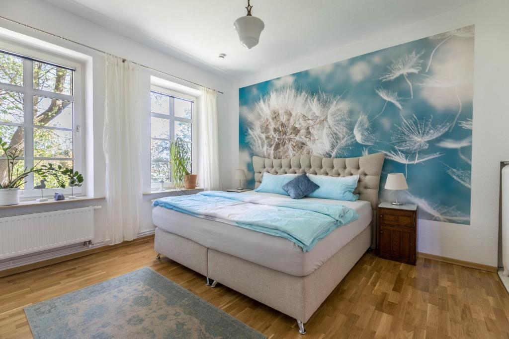 a bedroom with a bed with a blue painting on the wall at Haevn-Erholung, Fewo Sodalith in Reußenköge