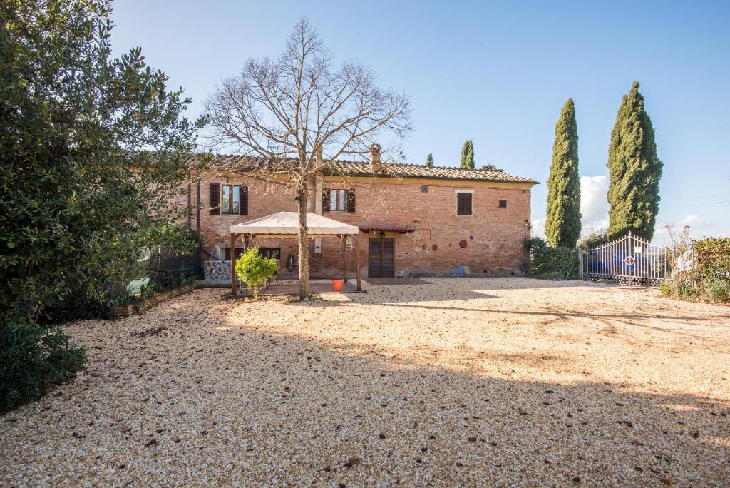 a large brick house with a tree in the yard at Casa Al Colle Buonconvento in Buonconvento