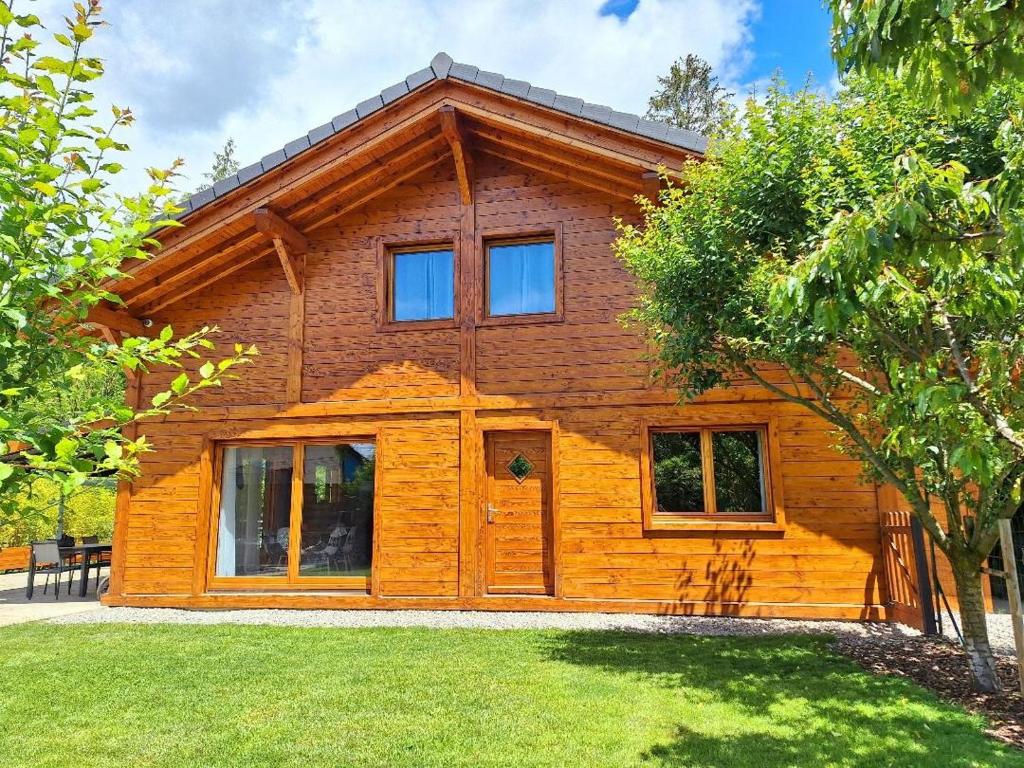 a large wooden house with a tree at Le Refuge - Faucigny in Faucigny
