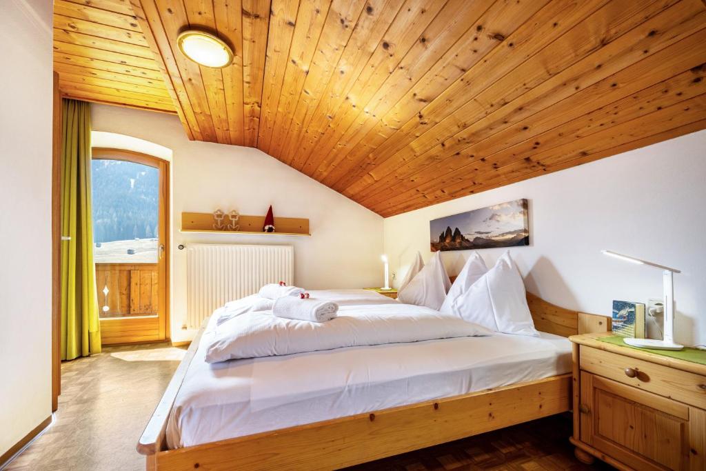 a bedroom with a large bed with a wooden ceiling at Manuel's App Watschinger Alpenrose in Sesto