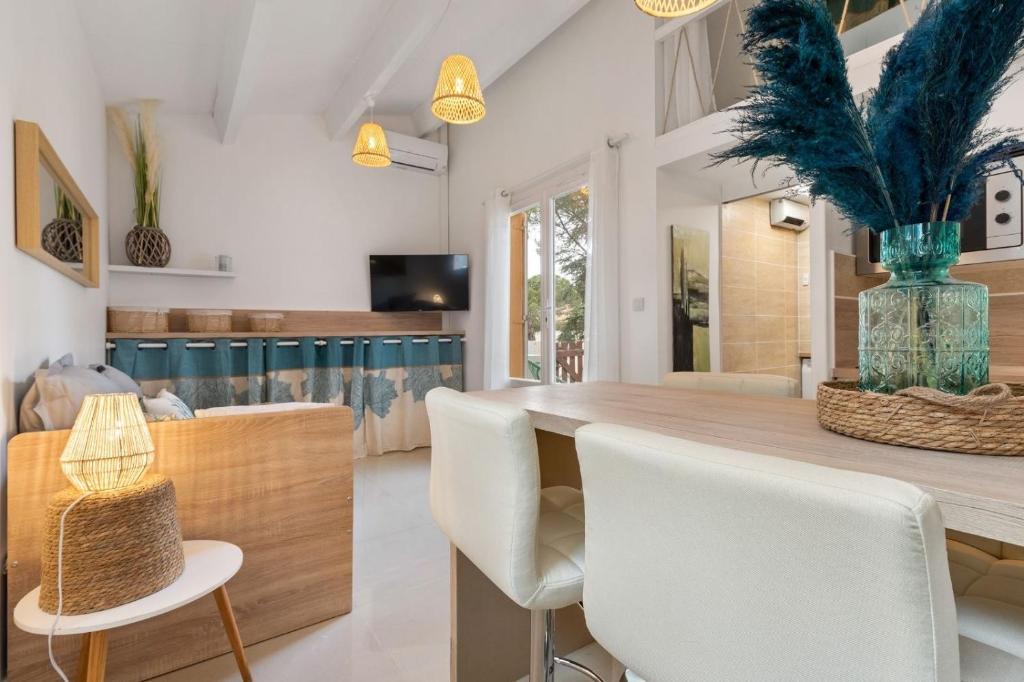 a dining room with a wooden table and white chairs at Appartement Pinède in Cap d'Agde