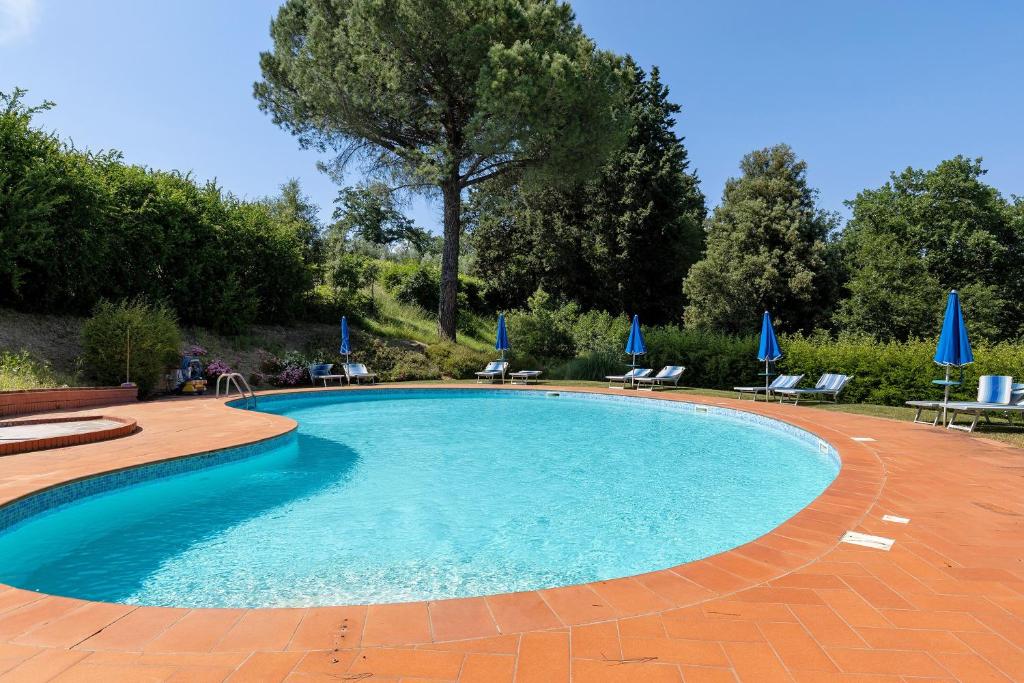 a swimming pool in a yard with chairs and umbrellas at La Ripa - Appartamento I Nidi in San Gimignano