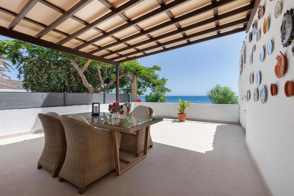an outdoor patio with a glass table and wicker chairs at La Lajita Beach Estudio in Lajita