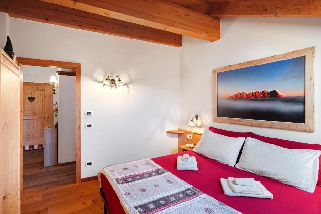 a bedroom with a red bed with a painting on the wall at Dimora La Rocca in Daiano