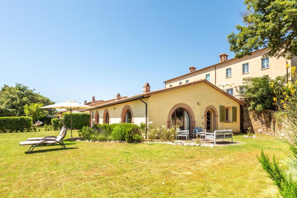 a building with a yard with a bench and an umbrella at Villa Falco in Trequanda