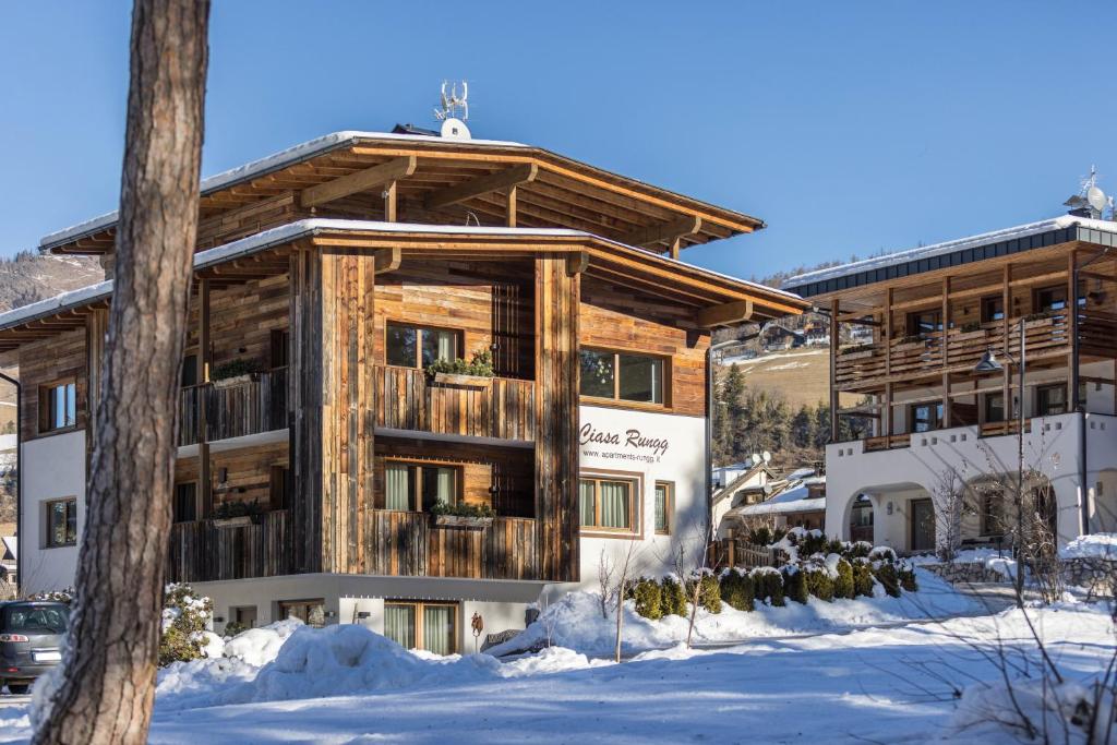 a large wooden building with snow in front of it at Ciasa Rungg Monte Sella Suite in San Vigilio Di Marebbe