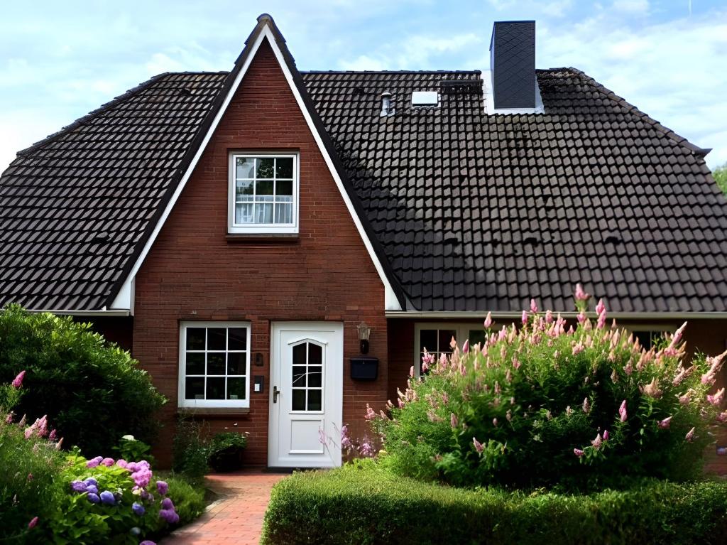 a house with a black roof and a white door at Ferienwohnung Ackerkoog in Niebüll