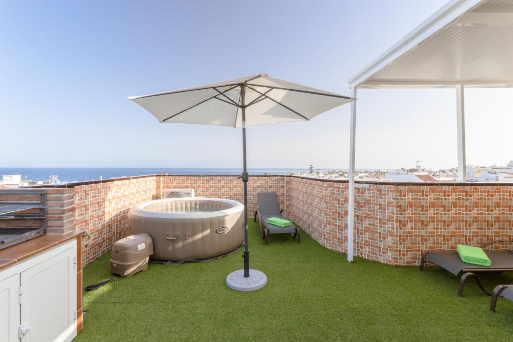 a hot tub on the roof of a building with an umbrella at Apartamento San Juan 18 in Nerja