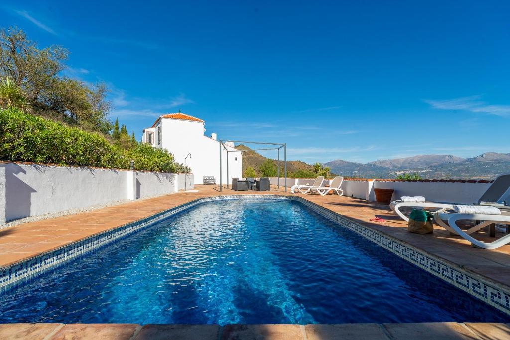 a swimming pool with a wooden deck and a house at Bravo spectacular views in Viñuela
