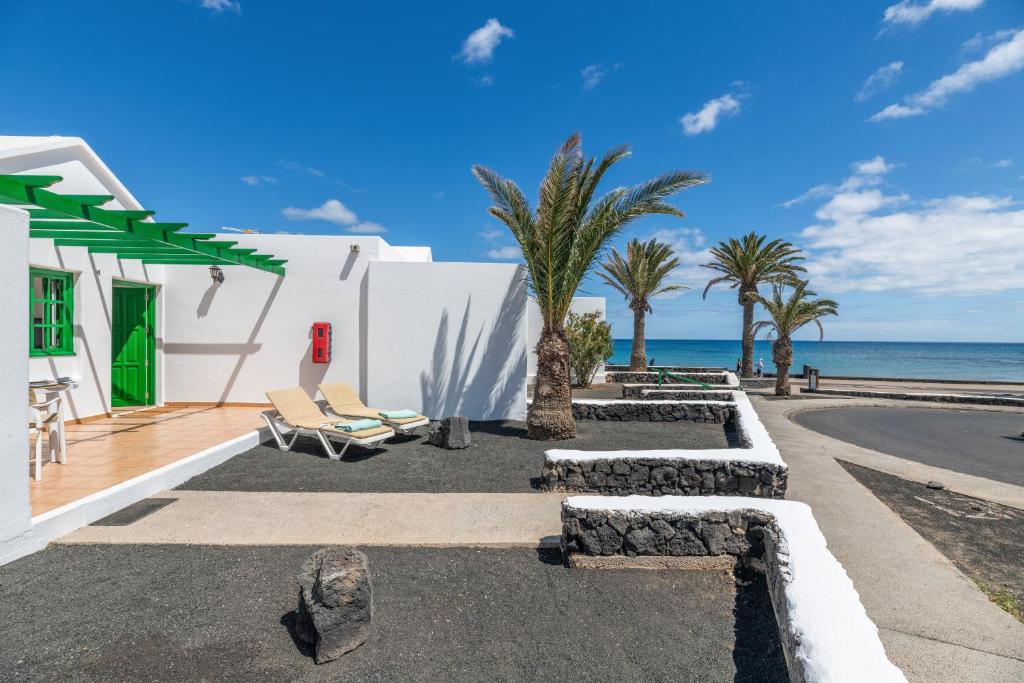 a white building with palm trees and the ocean at Bungalow Alma Ocean View in Puerto del Carmen