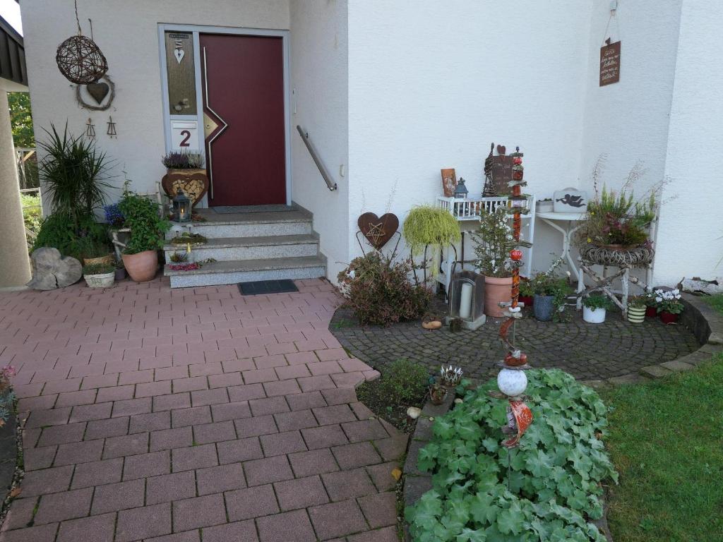a front yard with a red door and some plants at Ferienwohnung Schneckenhaus in Ofterdingen