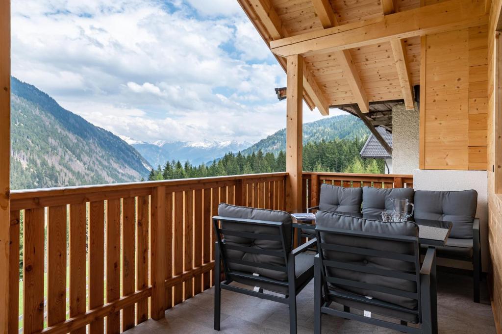 a deck with chairs and a table with a view at Blosegghof Bergchalets Talblick in Racines