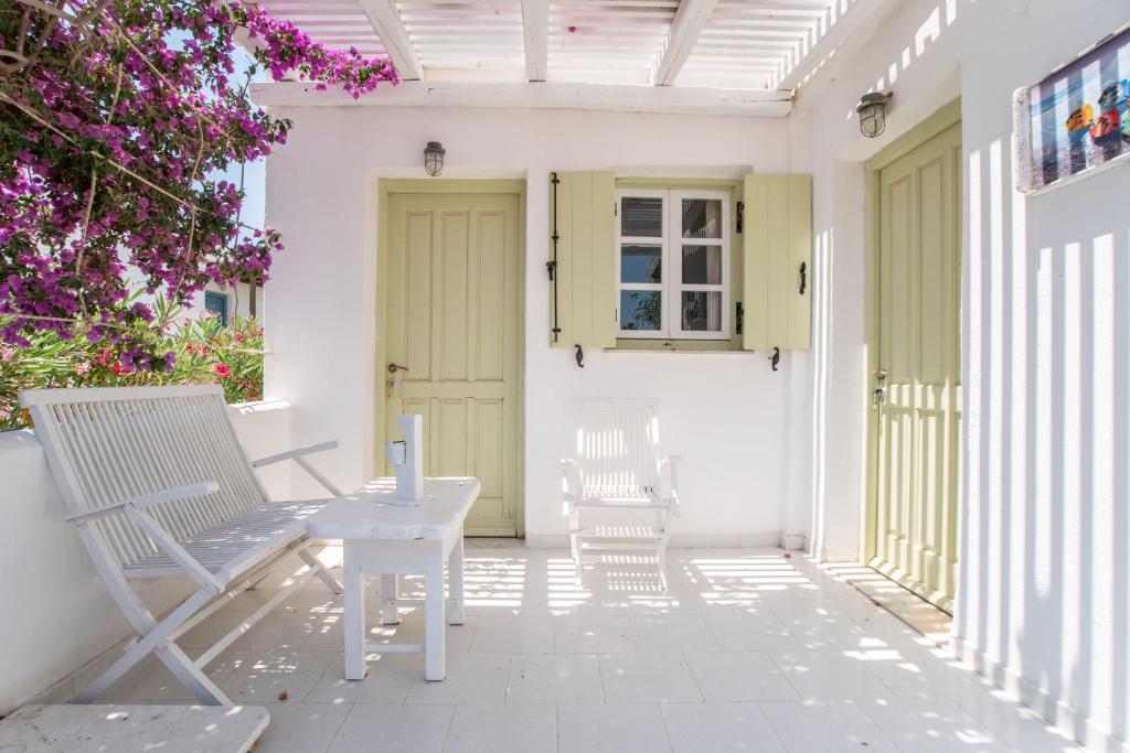 a patio with two white chairs and a yellow door at Green Retreats 4 Paros in Isterni