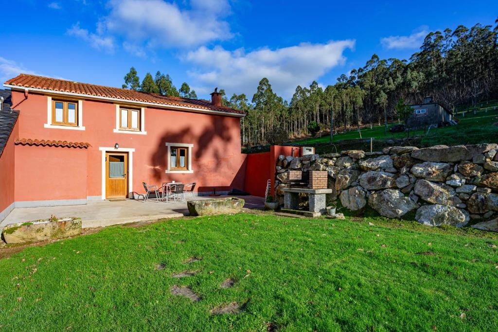 a house with a stone wall and a yard at Esteiro in Céltigos