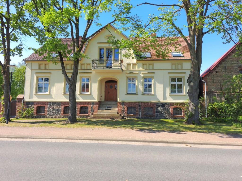 a large yellow house with trees in front of it at Ferienhof Schönberg in Lindow