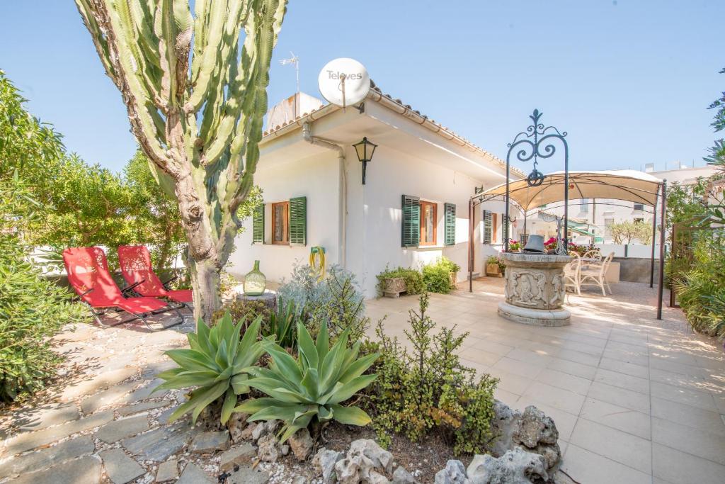a house with a patio with chairs and a tree at Finca el Cactus in Can Picafort