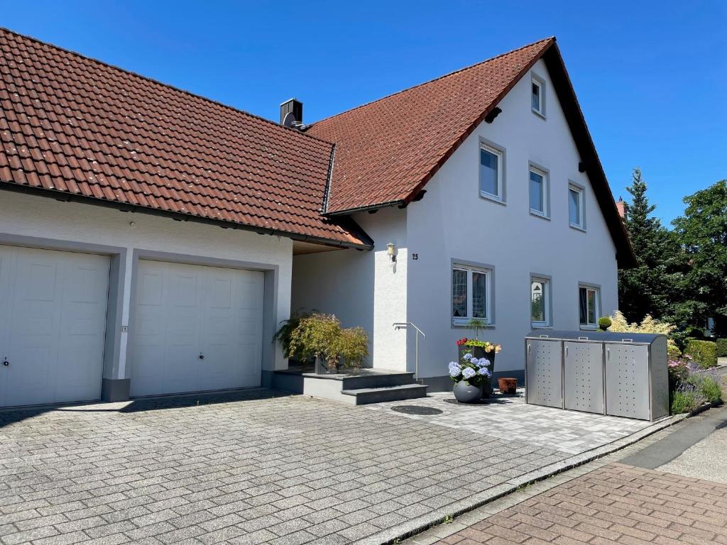 a white house with two garage doors and a roof at Ferienwohnung Heilsbronn in Heilsbronn