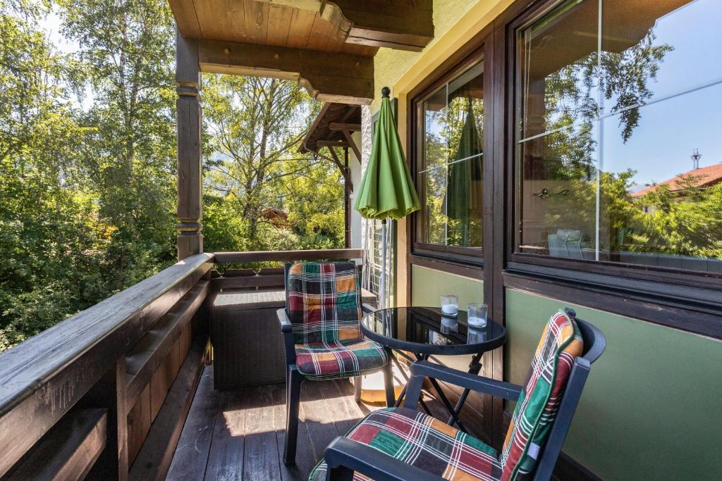 a porch with two chairs and a table and a window at Studio Bergblick in Inzell