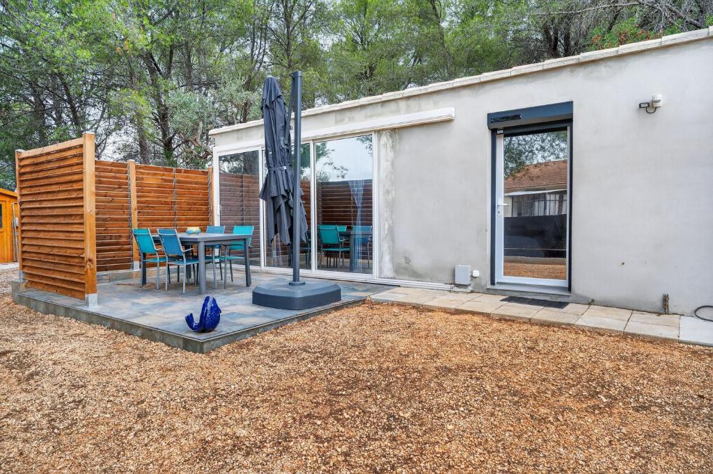 a patio with a table and an umbrella in front of a house at Cabanon des Amandiers avec terrasse in Sanary-sur-Mer