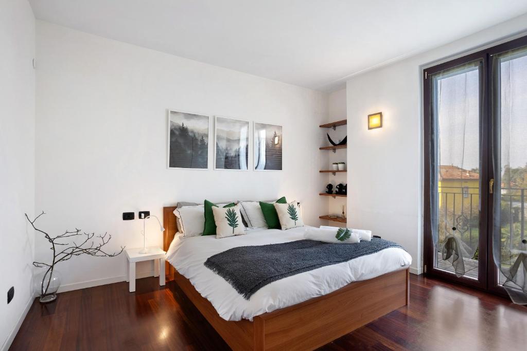 a white bedroom with a bed and a large window at vb home brianza in Costa Masnaga