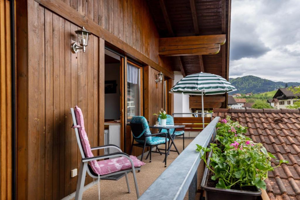 a balcony with chairs and a table and an umbrella at Gästehaus Erd - Fewo Grünten in Wertach