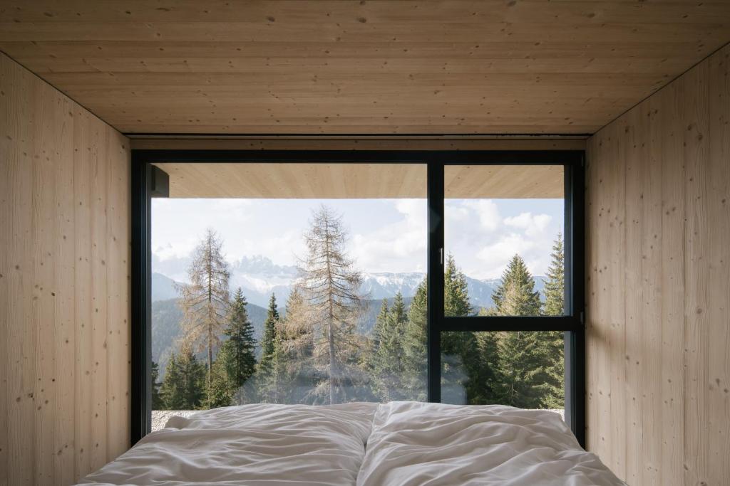 a bedroom with a large window looking out at the mountains at anders mountain suites 1 in Brixen