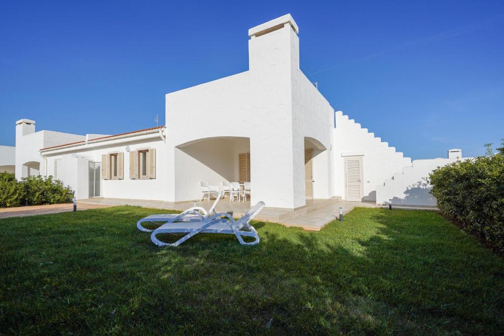 a white house with a lawn chair in the grass at Villa Terry in Ostuni
