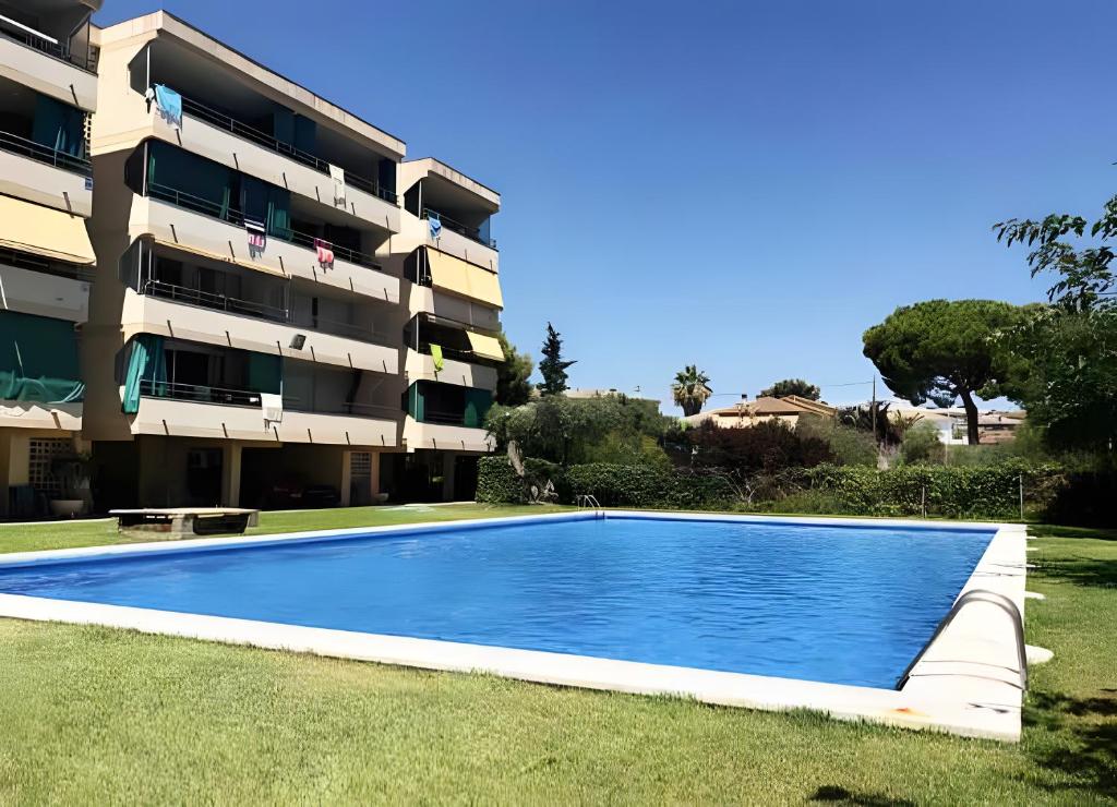 a swimming pool in front of a apartment building at Apartamento Francás in Comarruga