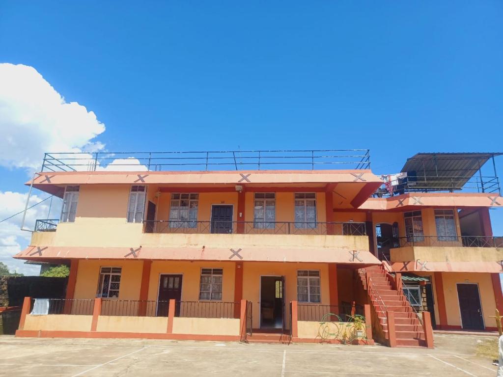 a large orange building with stairs in front of it at Melody residency in Cherrapunji