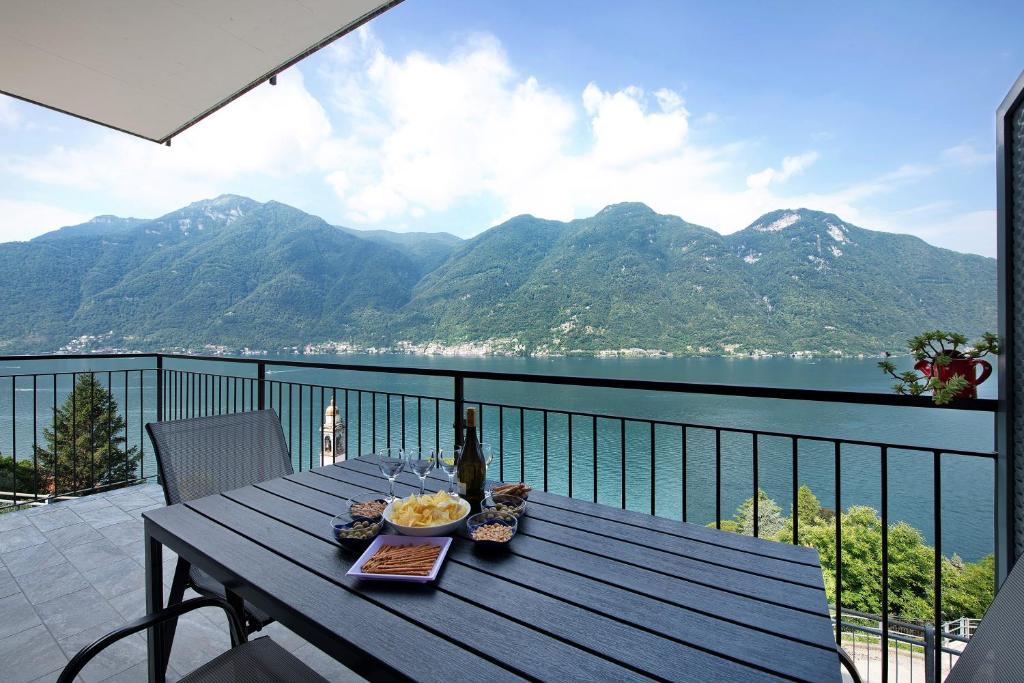 a table on a balcony with a view of the mountains at Appartamento 4 in Nesso