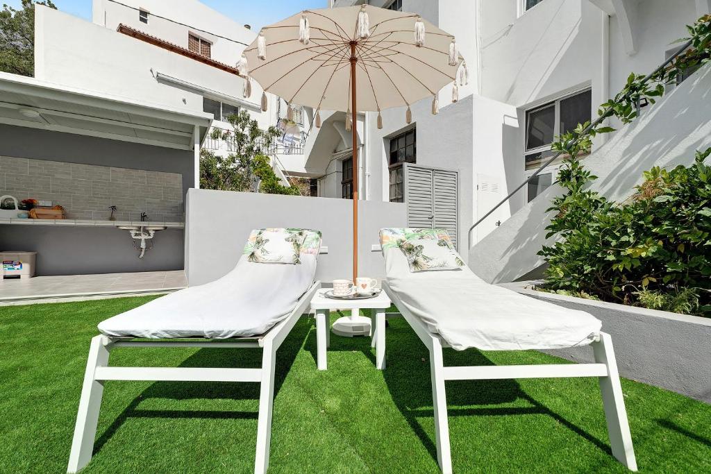 two chairs and a table with an umbrella on a lawn at Vista Alegre 22 B in El Paso