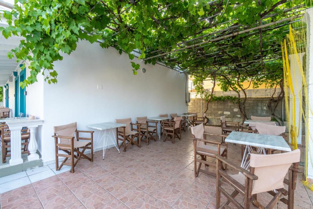 a patio with tables and chairs and trees at Pleasure Corfù Fish in Agios Georgios