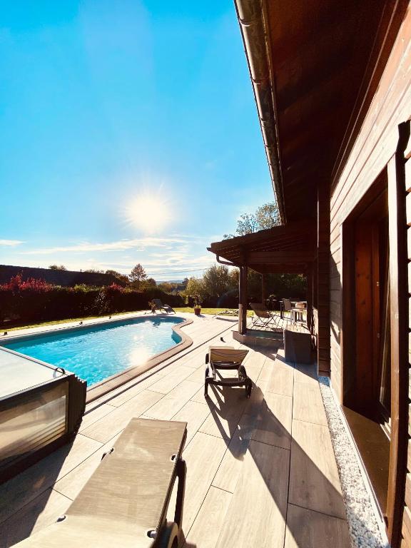 a patio with a table and chairs next to a swimming pool at Chalet des Lacs in Marigny