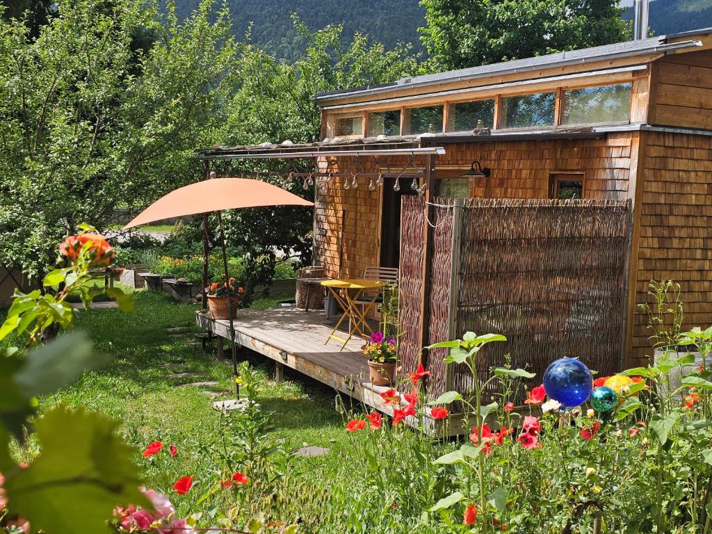 a wooden house with an umbrella in a garden at Loft Süd in Unterammergau
