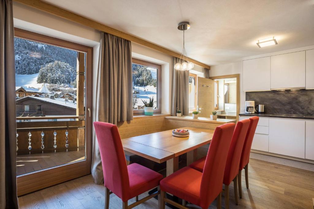 a kitchen and dining room with a wooden table and red chairs at Rosalpina Apt 2 in San Vigilio Di Marebbe