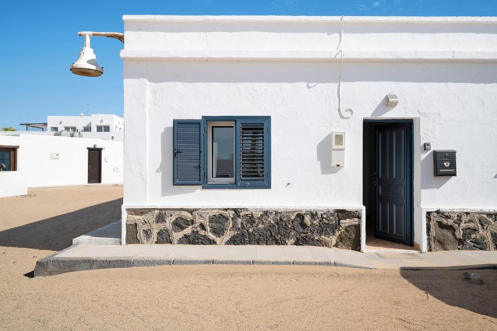 a white building with blue shutters and a door at Villa Sueños Zenoneisabel in Caleta de Sebo
