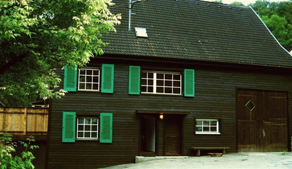a brown house with green shutters and a garage at Schwarzwaldbauernhaus Wutach in Lembach