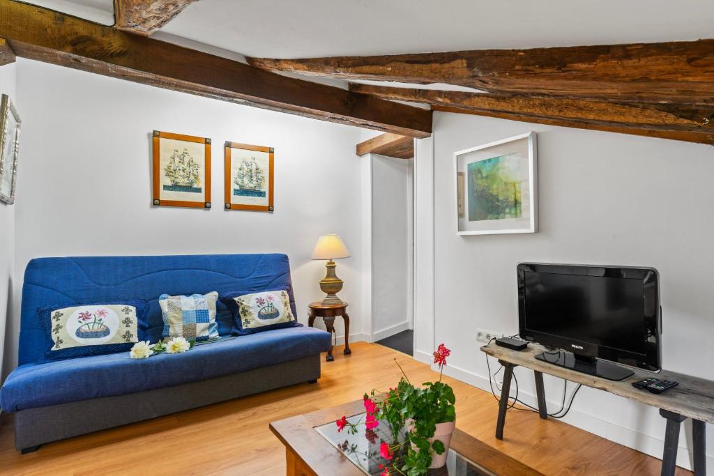 a living room with a blue couch and a tv at Apartamento 2 Casa Las Indianas in Selores