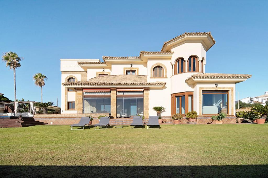 a large house with benches in a yard at Carolina Beach House in Chiclana de la Frontera
