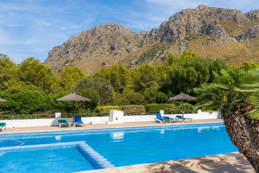 a swimming pool with chairs and mountains in the background at Garballo in Betlem