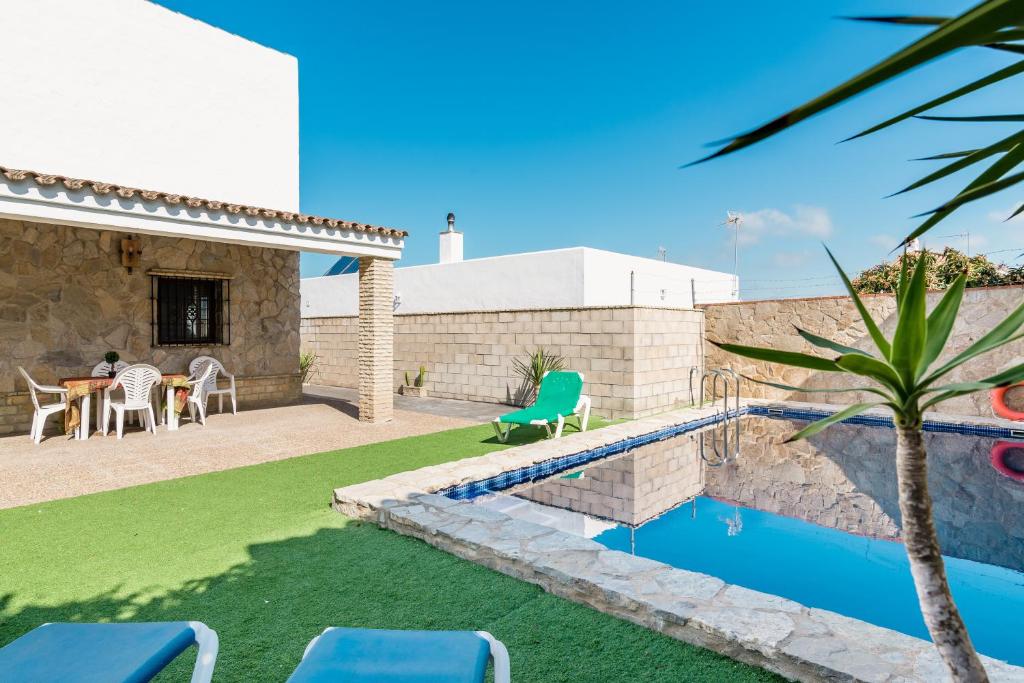 a backyard with a pool and a table and chairs at Chalet Aragon Muñoz in Conil de la Frontera