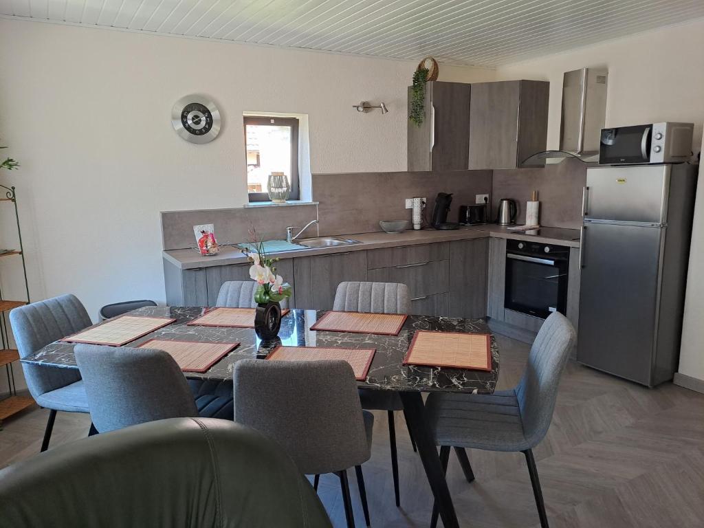 a kitchen with a table and chairs and a kitchen with a refrigerator at Maison Maurer in Aschbach