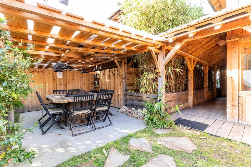 a patio with a table and chairs under a wooden pergola at Villa Bayani in Lacanau